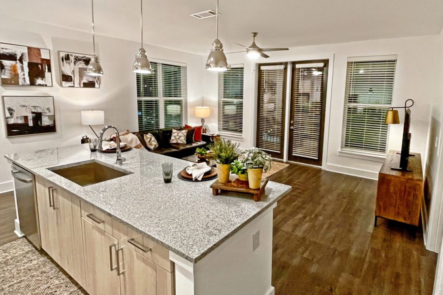 The Fieldhouse modern open kitchen and living room with granite island, wooden floors, large windows, and cozy decor.