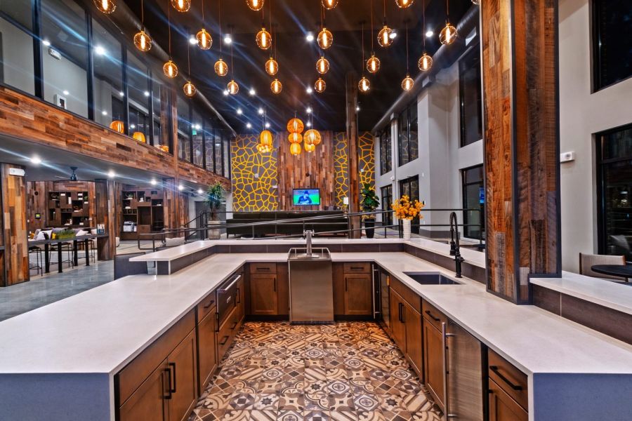 Modern, spacious kitchen with pendant lights, patterned tile floor, and wood accents throughout at The Fieldhouse Apartments.
